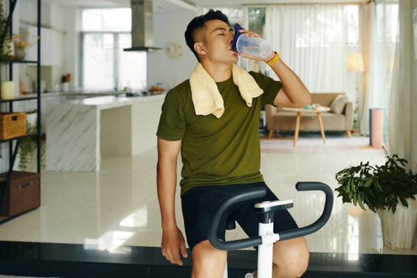Man drinking from a water bottle after exercise in a home setting